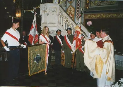 Poświęcenie sztandaru w kościele: kapłan, poczet sztandarowy, rozwinięty sztandar.