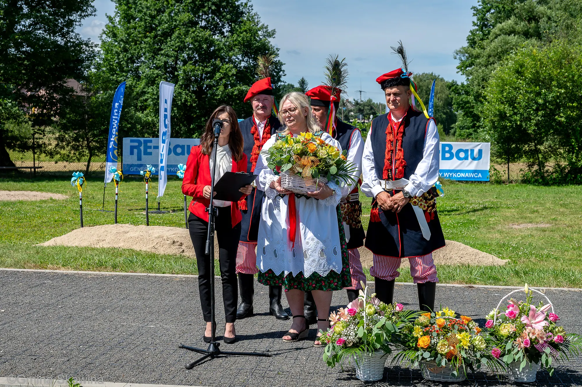 Uczestniczki w strojach ludowych z bukietami kwiatów.